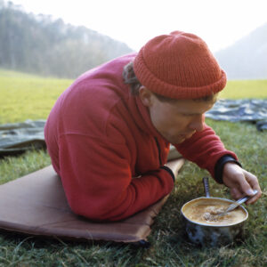 Man in the wilderness eating soup he cooked with survival food recipe