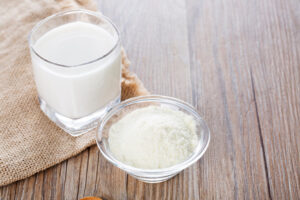 glass of milk made with powdered milk next to bowl of powdered milk used to make survival food