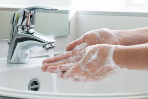 soapy hands underneath a stream of running water at a sink