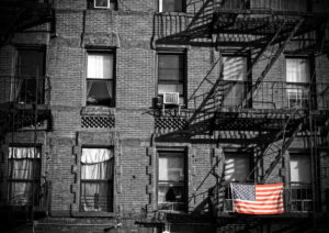 black and white apartment building with colored American flag hanging outside