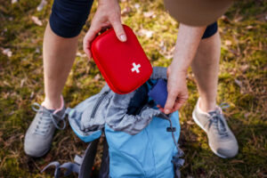 woman placing red first aid kit pouch into a light blue drawstring backpack